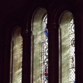 Sun shines through three oval stained glass windows in cathedral